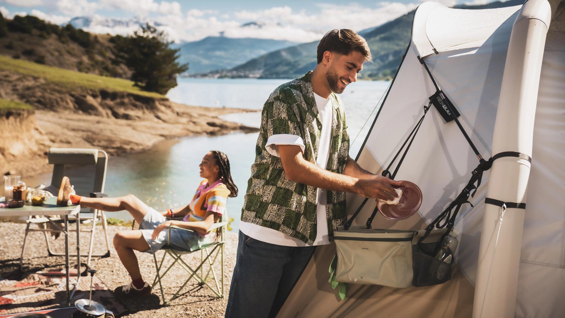 Zwei Freunde haben eine Camping-Kühltasche vor ihrem Zelt am See stehen