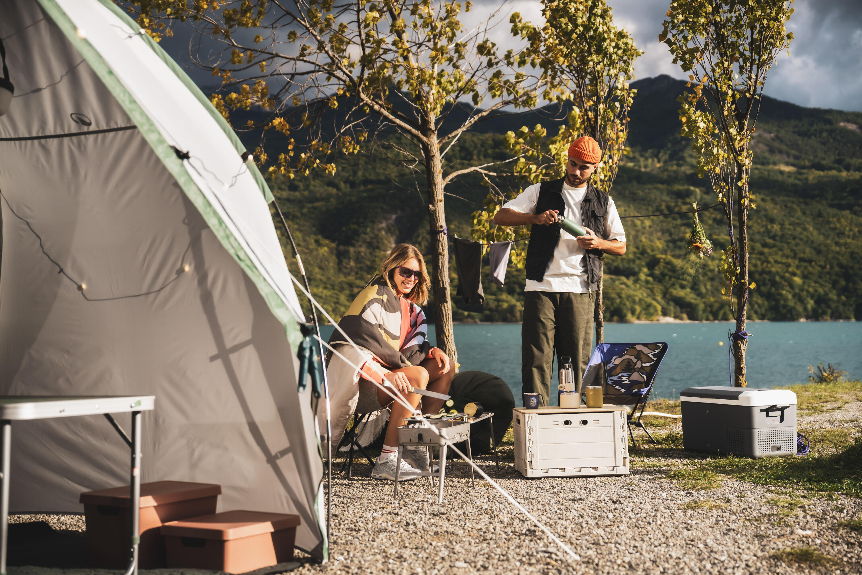 man en vrouw zijn aan het barbecuen bij hun kampeerplek aan het water