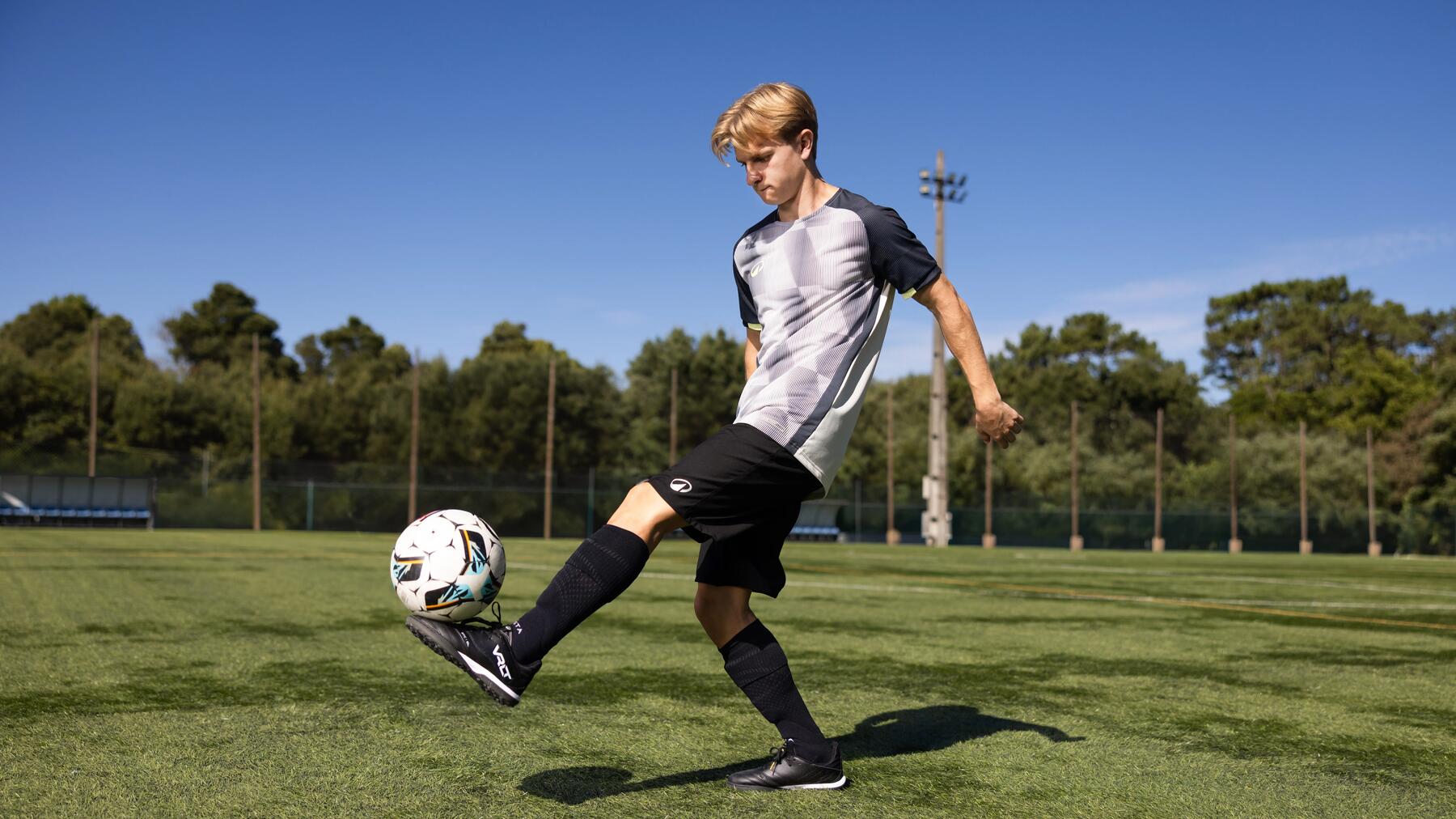 Ein Junge spielt Fußball auf dem Platz in passender Kleidung