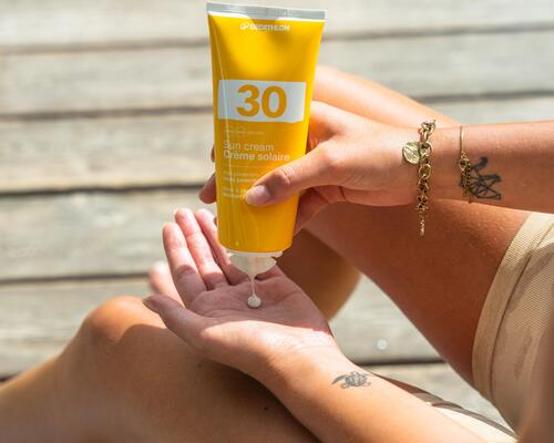 Femme versant de la crème solaire sur sa main