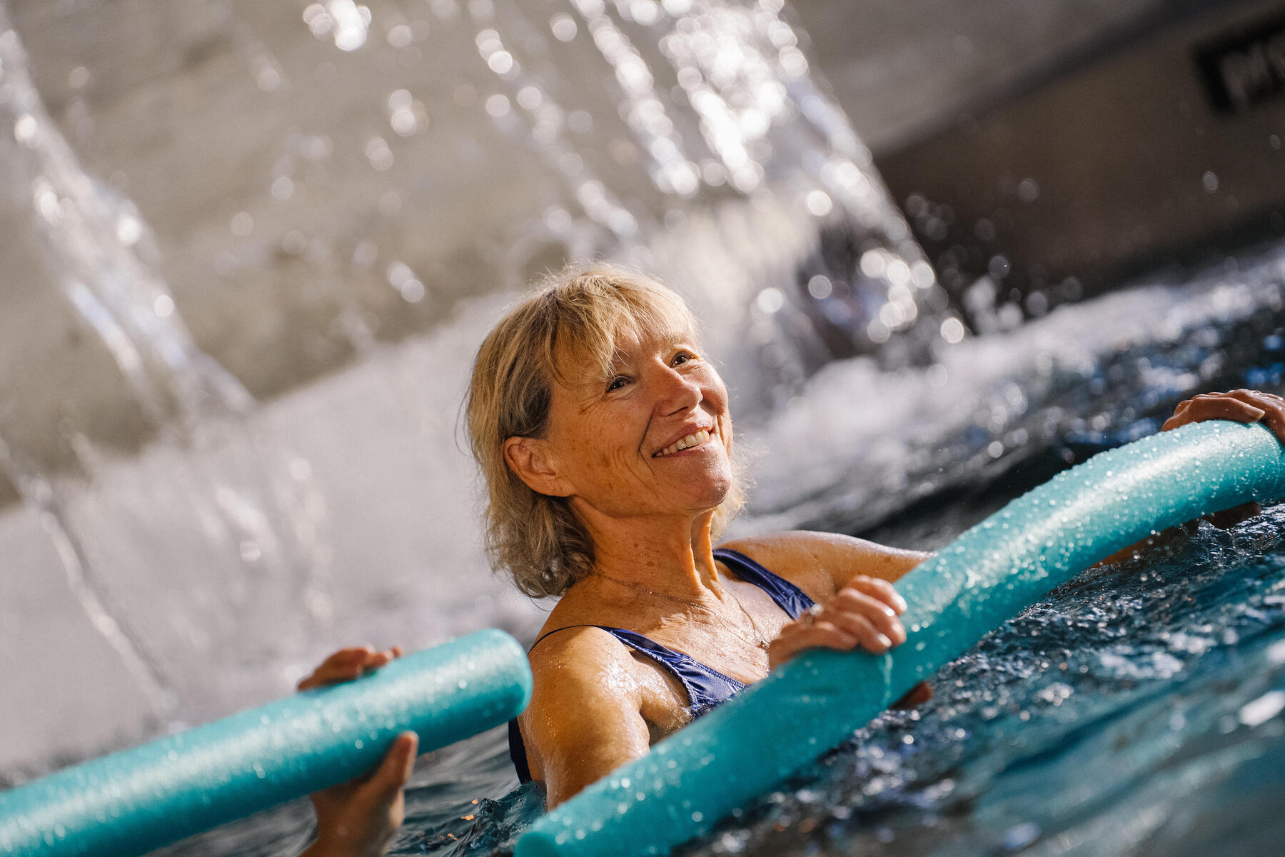 Kobieta ćwicząca z makaronem aqua aerobic w basenie