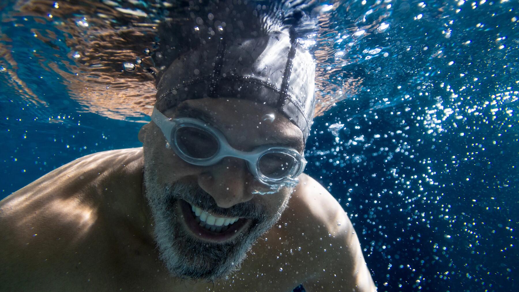 Mann trägt Badekappe und Schwimmbrille