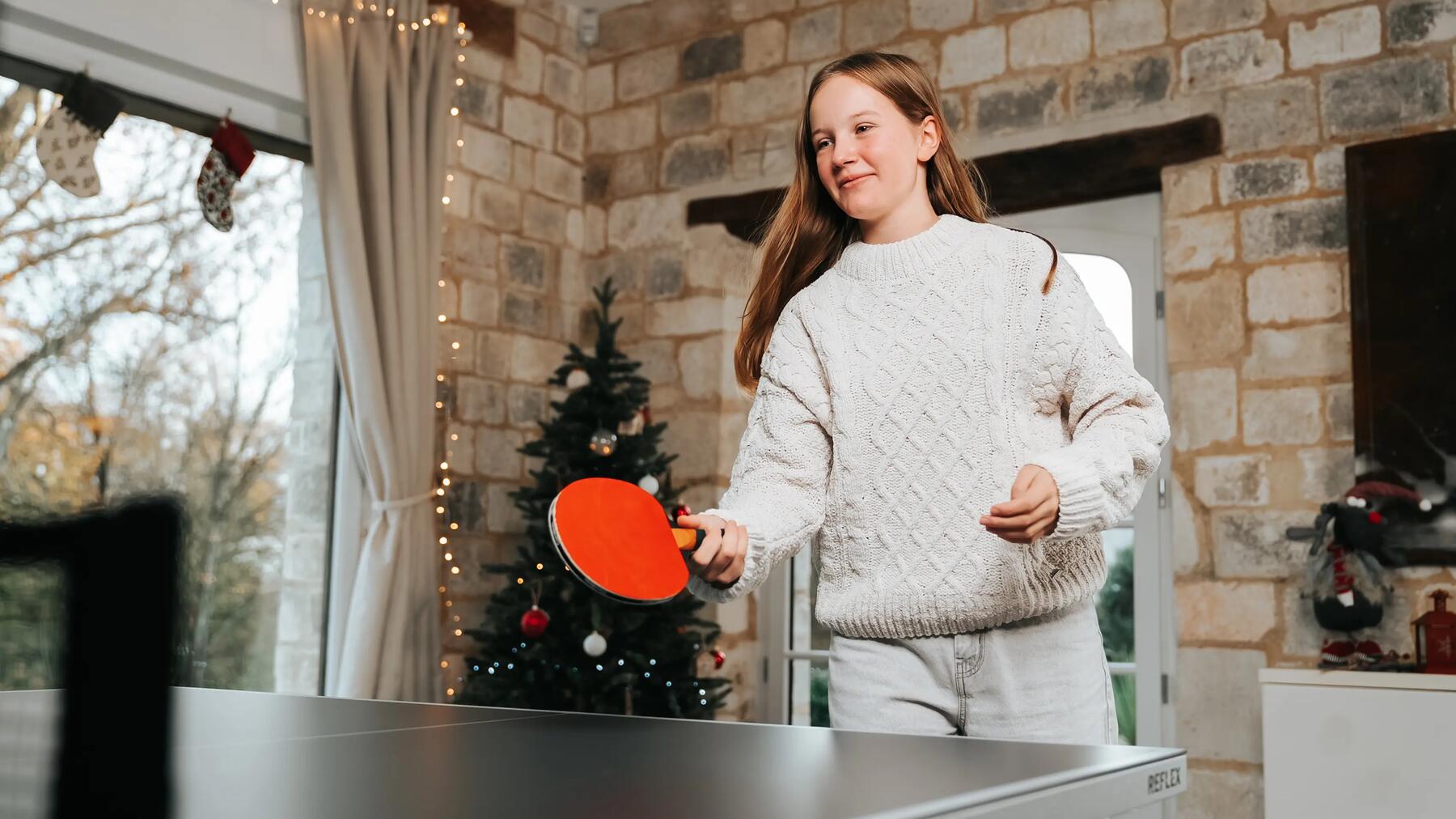 Ein Mädchen spiel zu Weihnachten Tischtennis mit einem Schläger