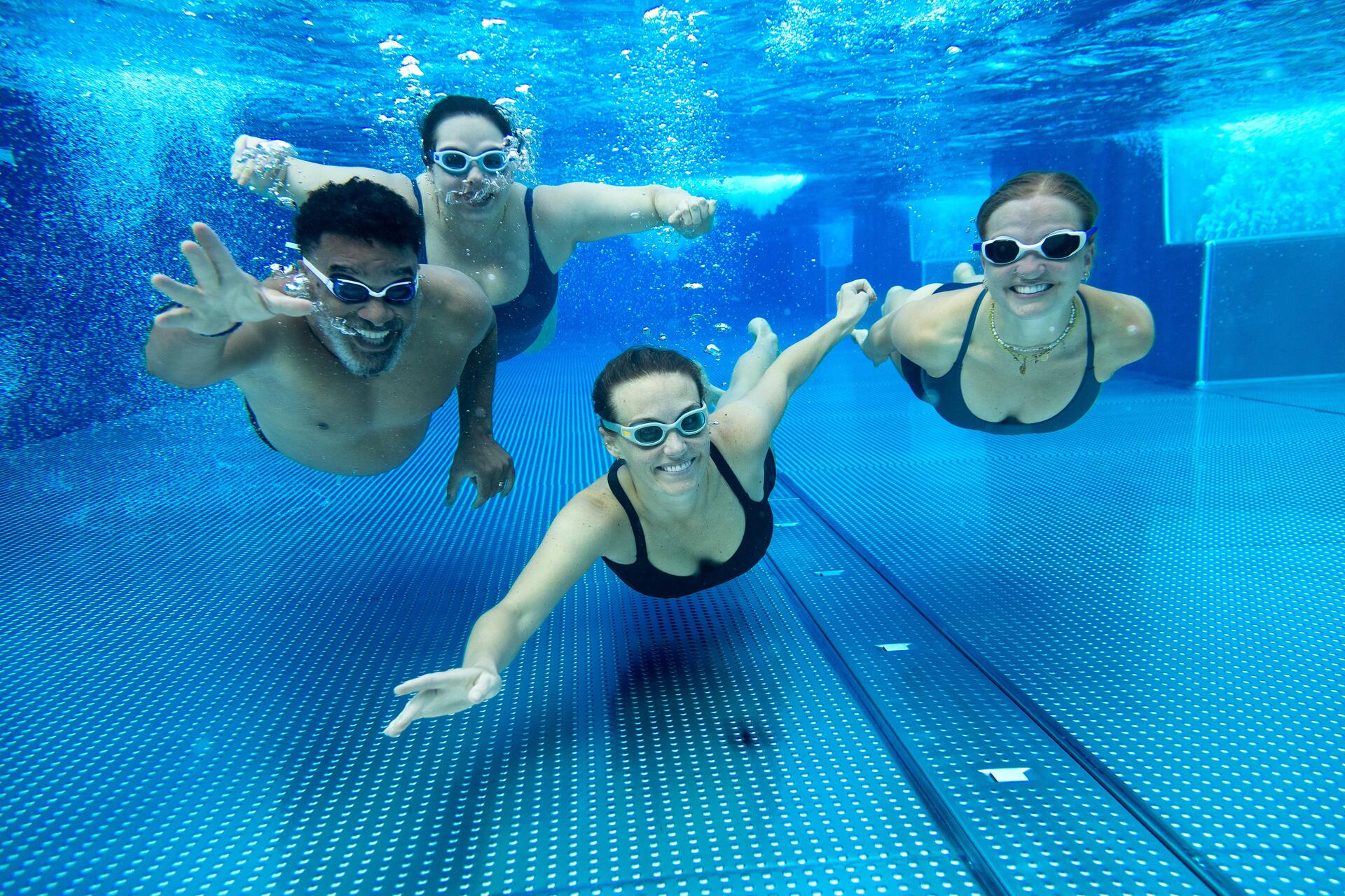Woman swimming underwater wearing a cap and goggles
