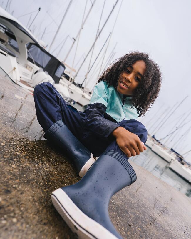 un jeune garçon assis sur un quai dans de l'eau