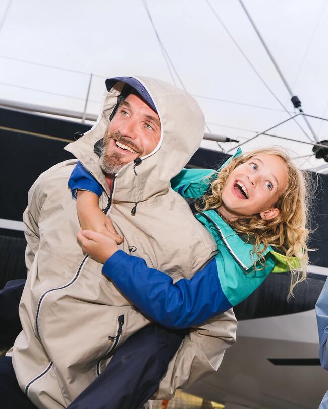 man wearing a beige rain jacket carrying a kid on his back