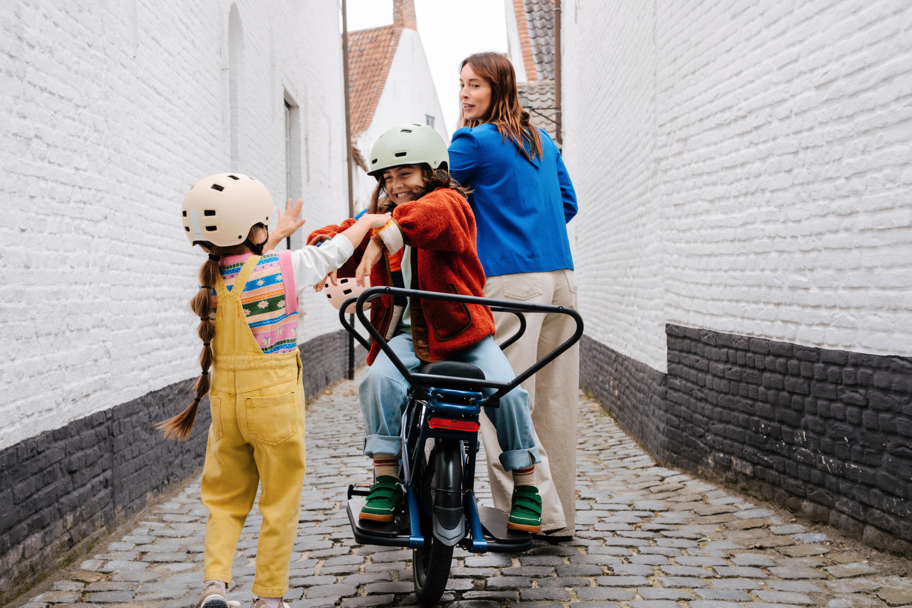 vrouw met twee kids die op de longtail cargo stappen