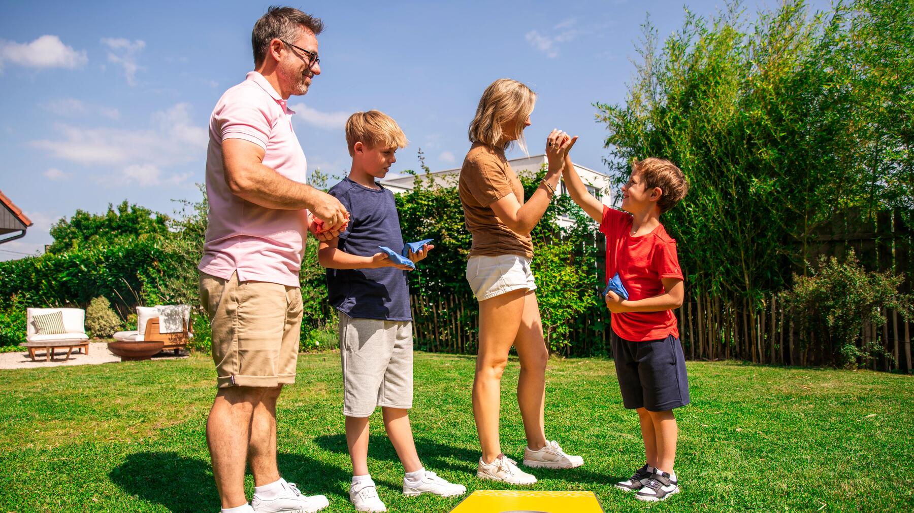 Een familie speeltje een potje cornhole in hun tuin