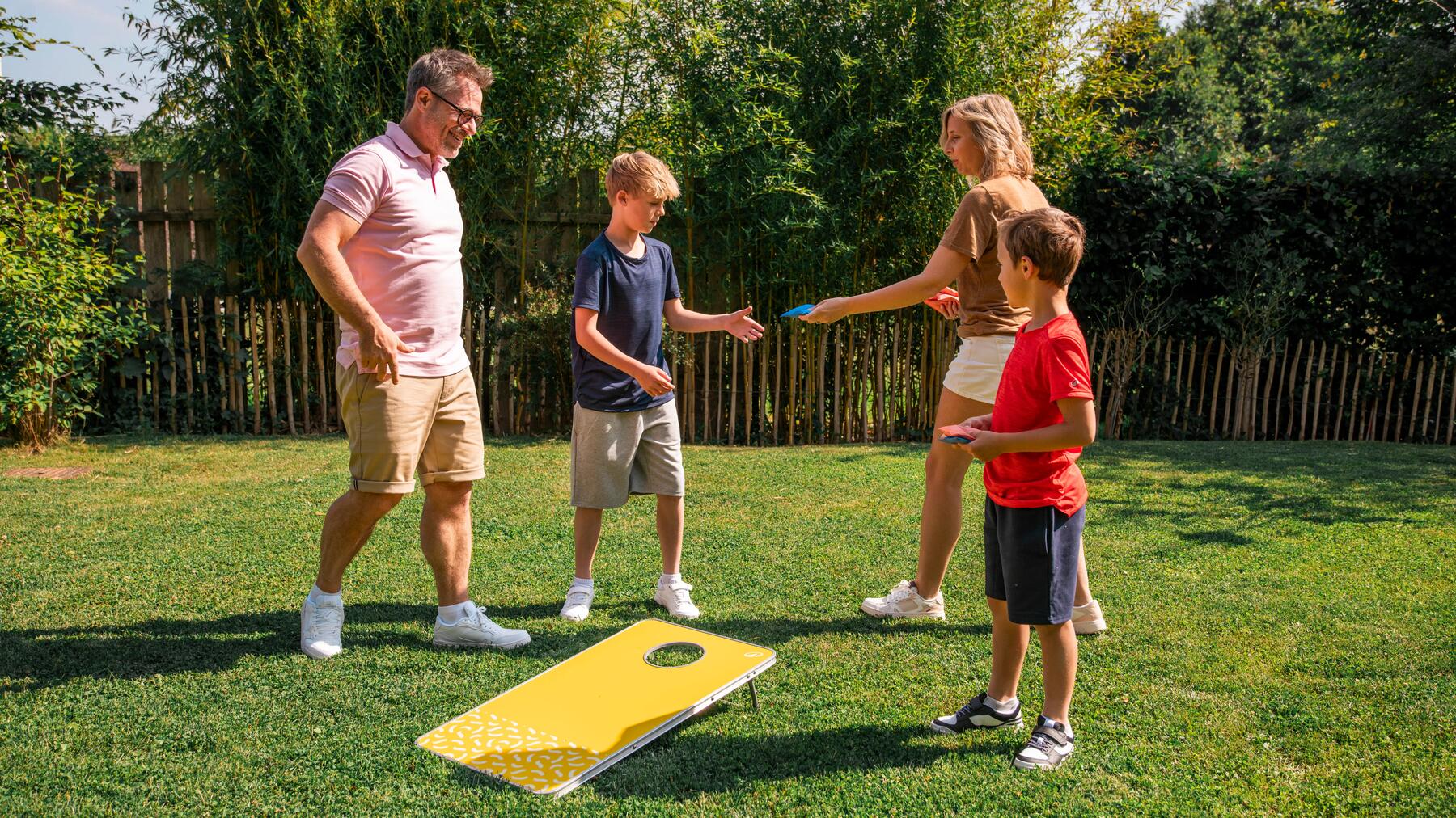 Een gezin van vier speelt cornhole in hun tuin