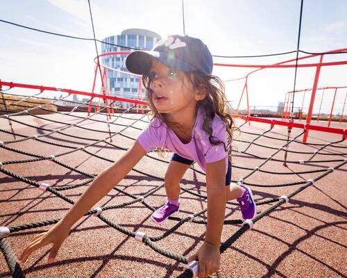 Ein Kind klettert auf dem Spielplatz mit einem UV-Shirt