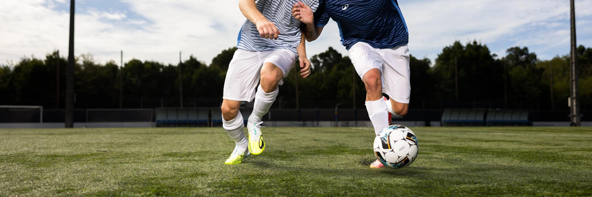 Zwei Fußballspieler in blau-weiß gestreiften Trikots kämpfen auf einem Rasenplatz in einem intensiven Laufduell um den Ball.