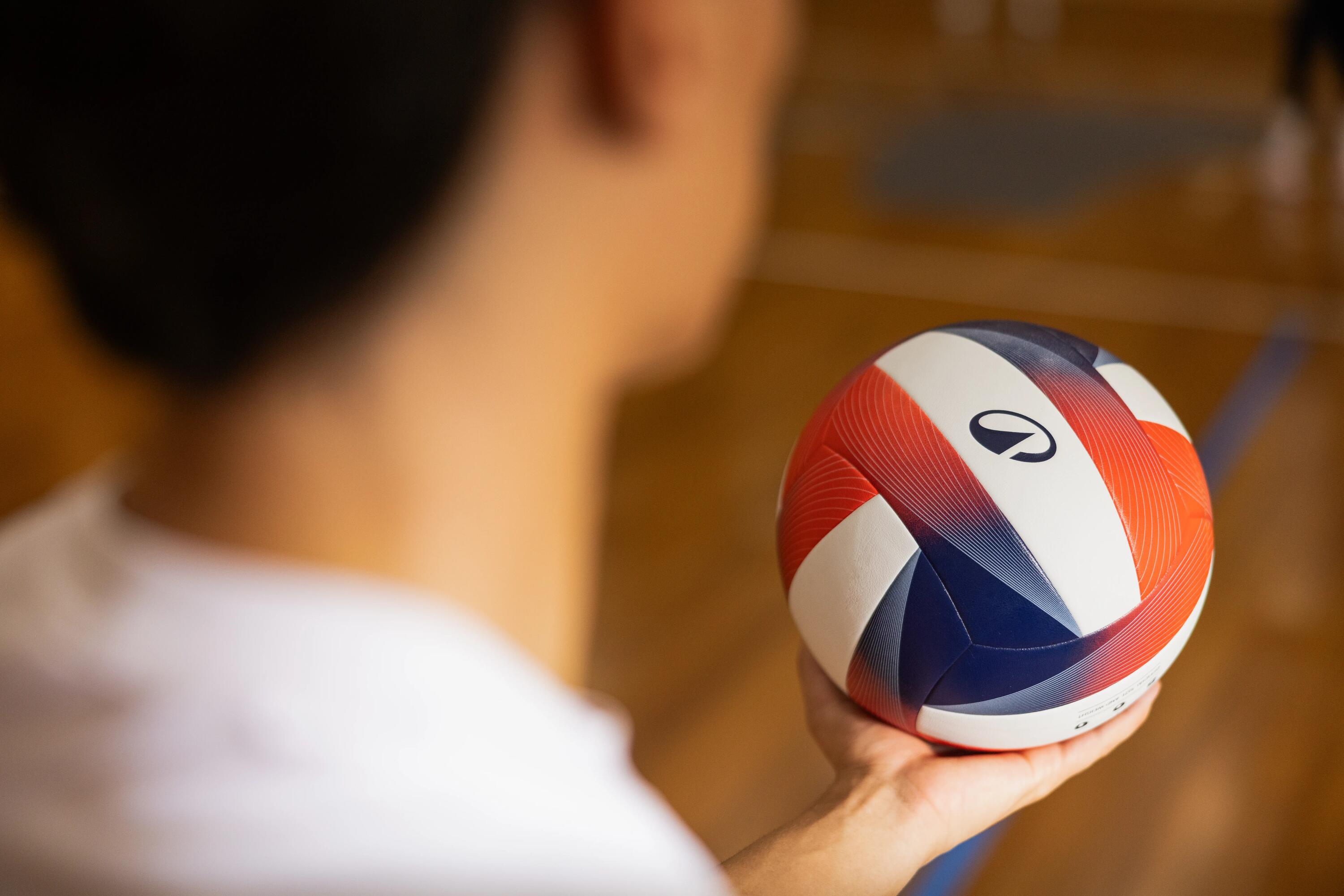 Blick über die Schulter einer Person, die einen Kipsta-Volleyball auf der Handfläche hält.