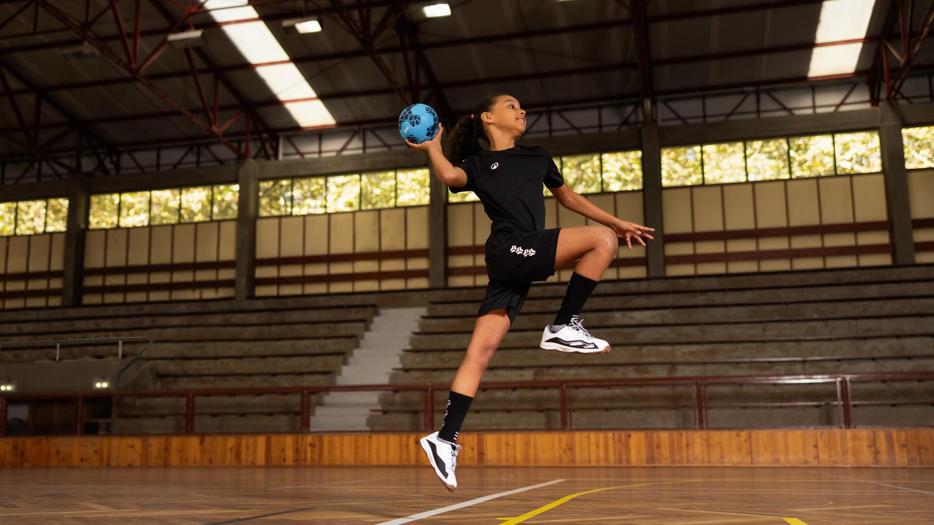 criança a saltar com bola de andebol na mão