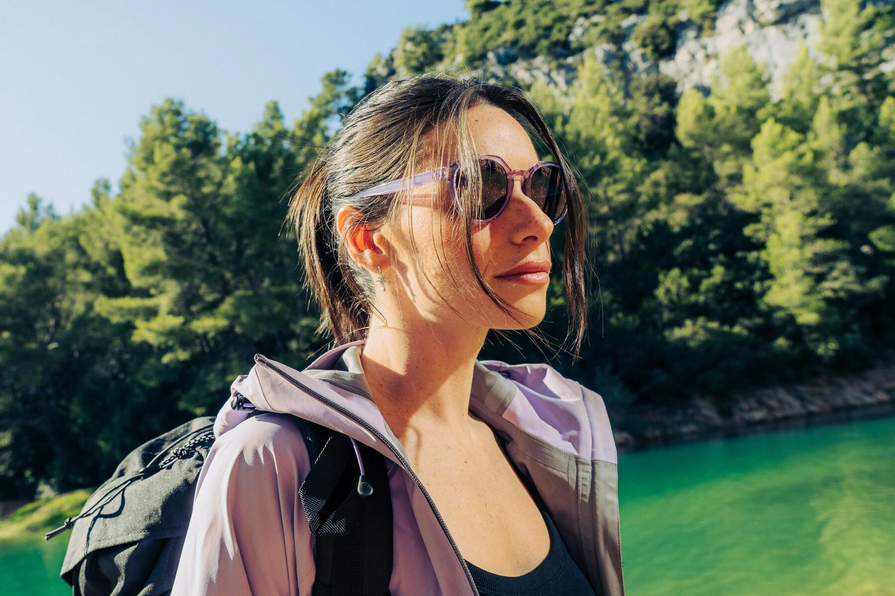 Eine Frau steht an einem See und trägt eine Sportsonnebrille