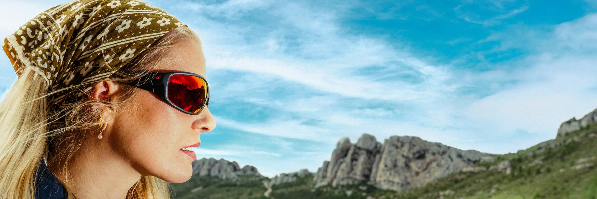 Femme qui porte un bandana et une paire de lunettes de soleil polarisé, elle est en randonnée dans les montagnes
