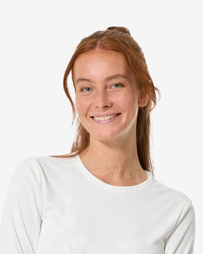 Surfer auf blauem Wasser, umgeben von grünen Bäumen und Felsen, unter klarem Himmel.
