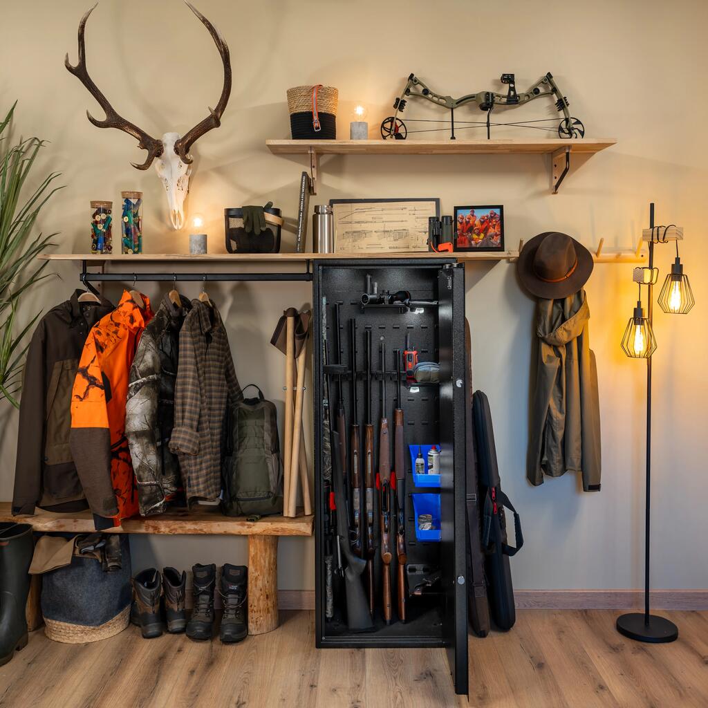 Ein Jagdzimmer mit einem Waffenschrank, Jagdbekleidung und einem Geweih an der Wandnem