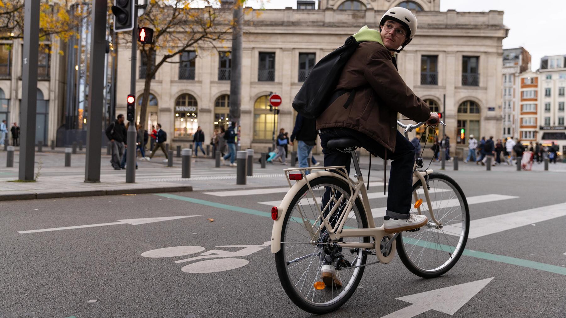 Mann mit Fahrradhelm und Rucksack auf dem Rücken auf dem Fahrrad in der Stadt.