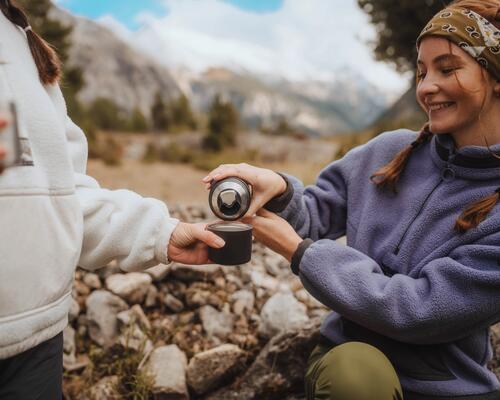 Eine Frau trägt Fleece und schenkt einen Tee ein