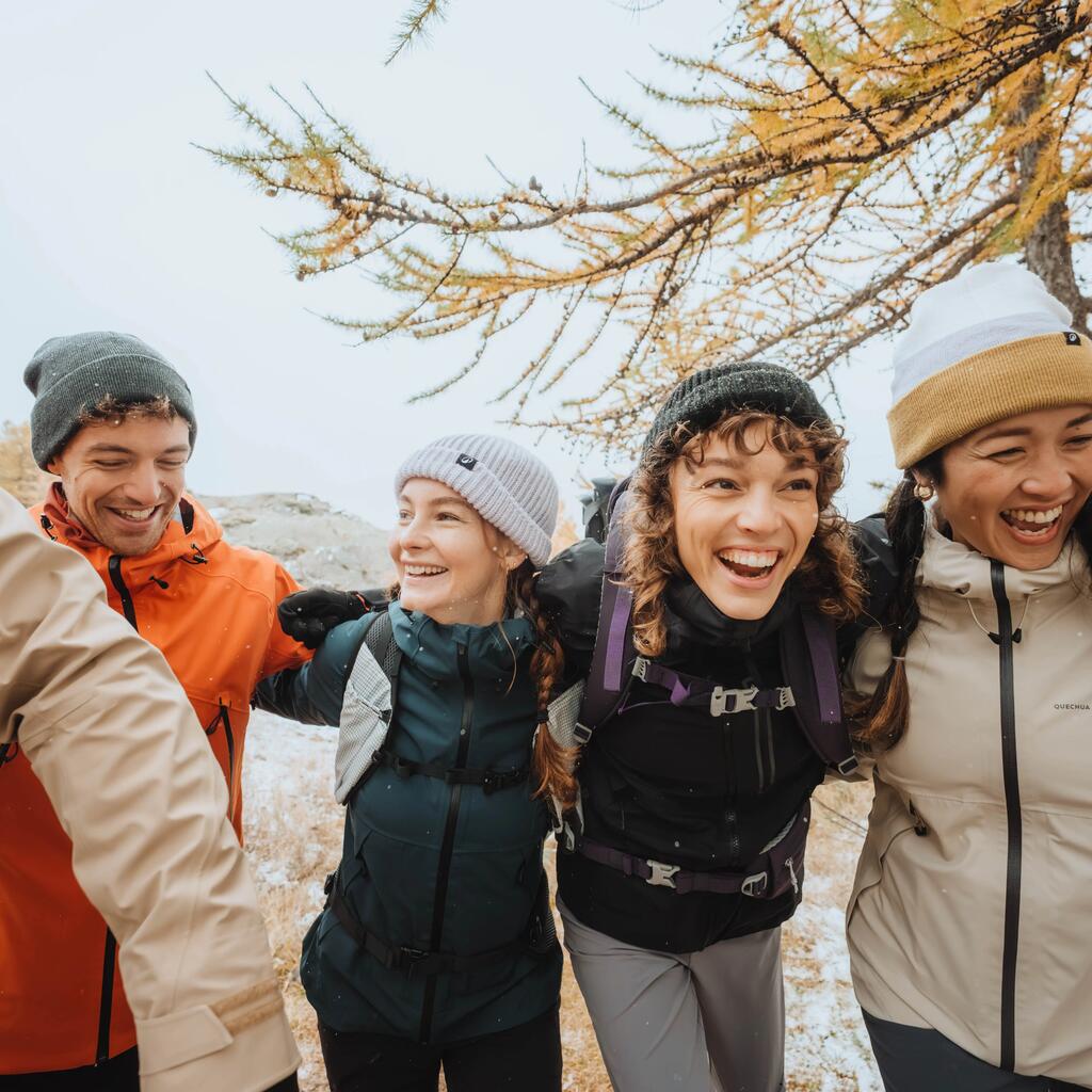 Eine Freundesgruppe beim Wandern mit warmen Hauben auf den Köpfen.