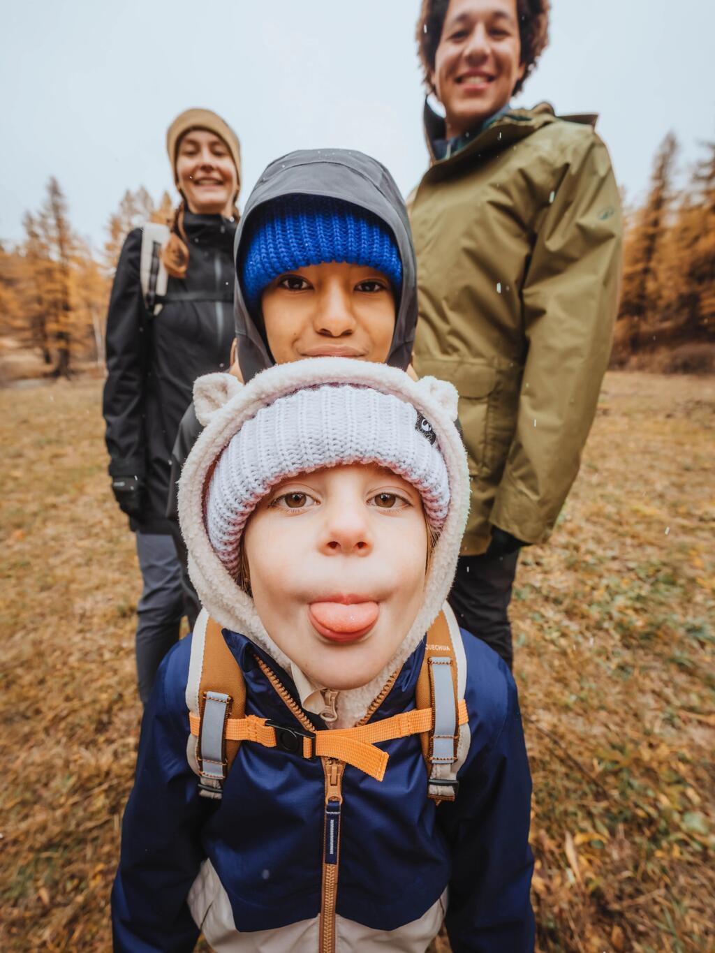 Eine Familie auf einem Selfie im Freien bei herbstlichen Wetter. Alle tragen warme Kleidung.