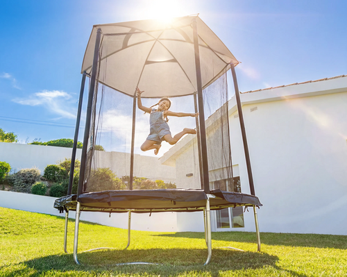 Jeune fille qui saute sur un trampoline extérieur dans un jardin
