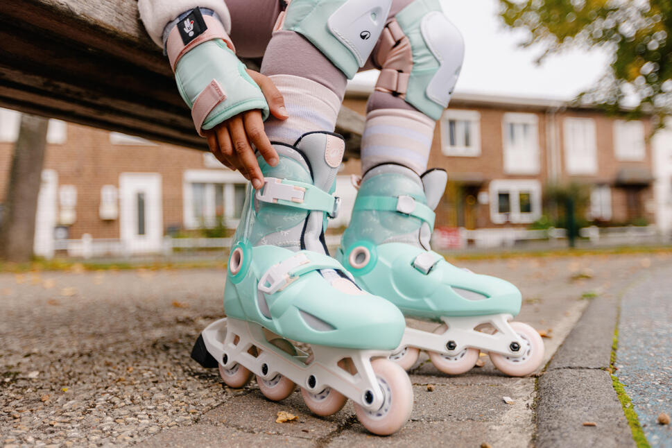 Dete koje sedi na klupi i popravlja menta zelene Oxelo Play 5 rolere