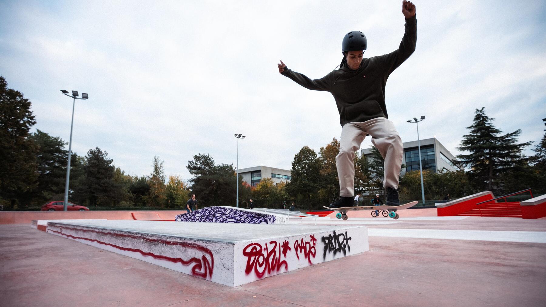Ein erwachsener Skateboarder vollführt einen Sprung-Trick in der Luft