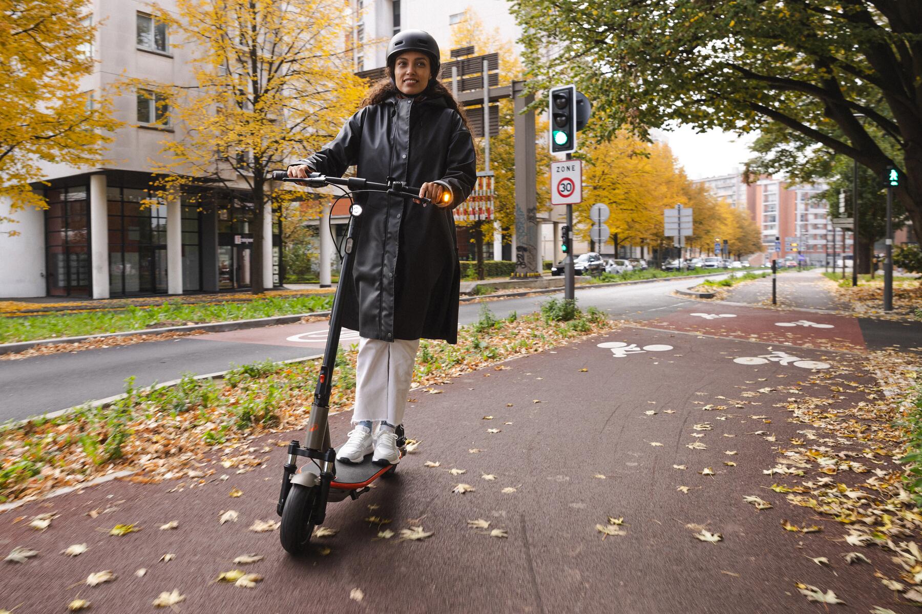 Kobieta w kasku jadąca hulajnogą elektryczną po ścieżce dla rowerów