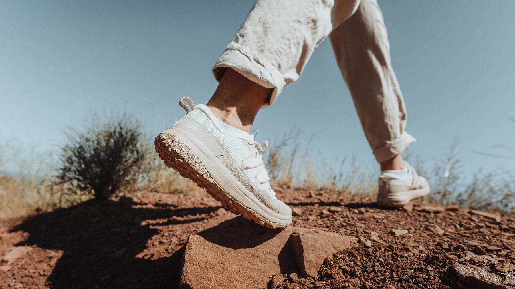 Ein Mann trägt weiße Wanderschuhe auf einem erdigen Weg