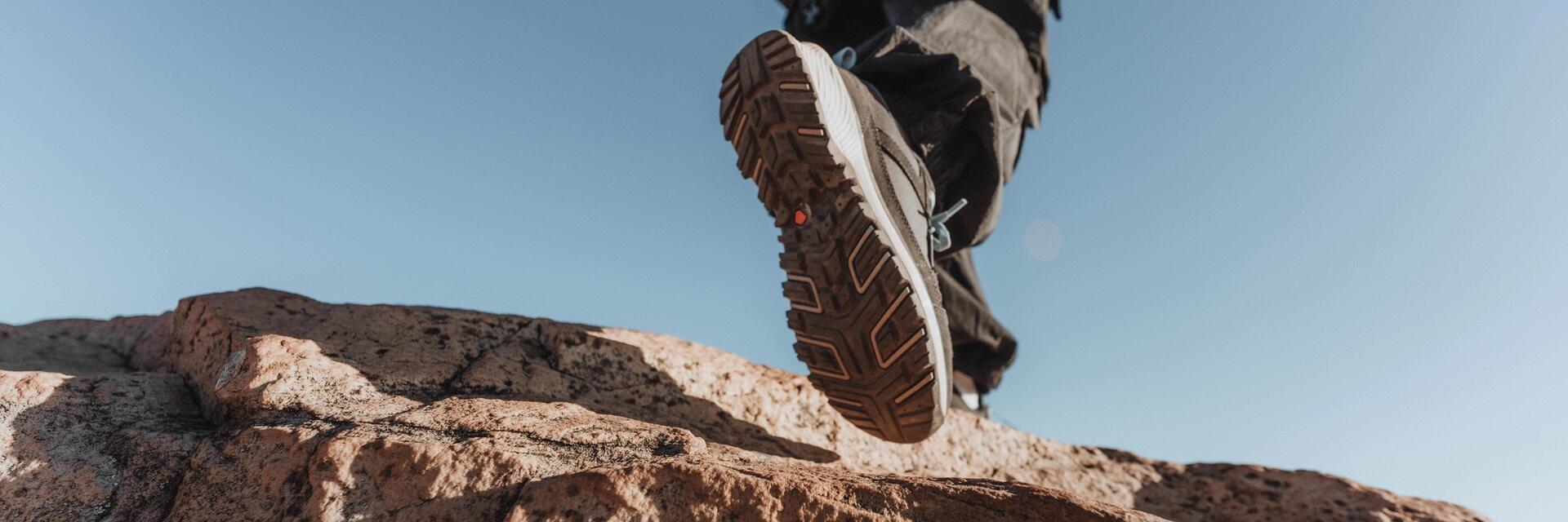 Eine Person trägt Wanderschuhe auf einem Felsen unter blauem Himmel