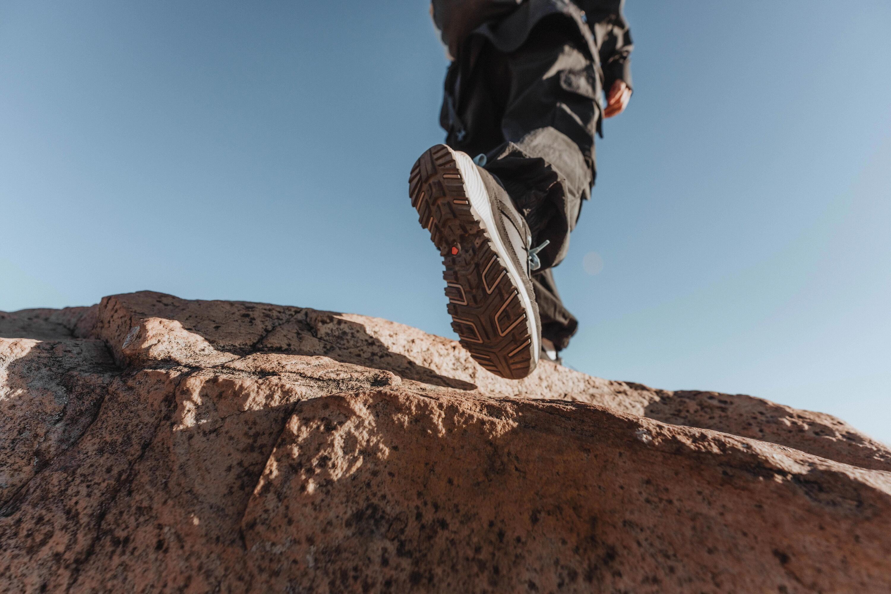 Eine Person trägt Wanderschuhe auf einem Felsen unter blauem Himmel