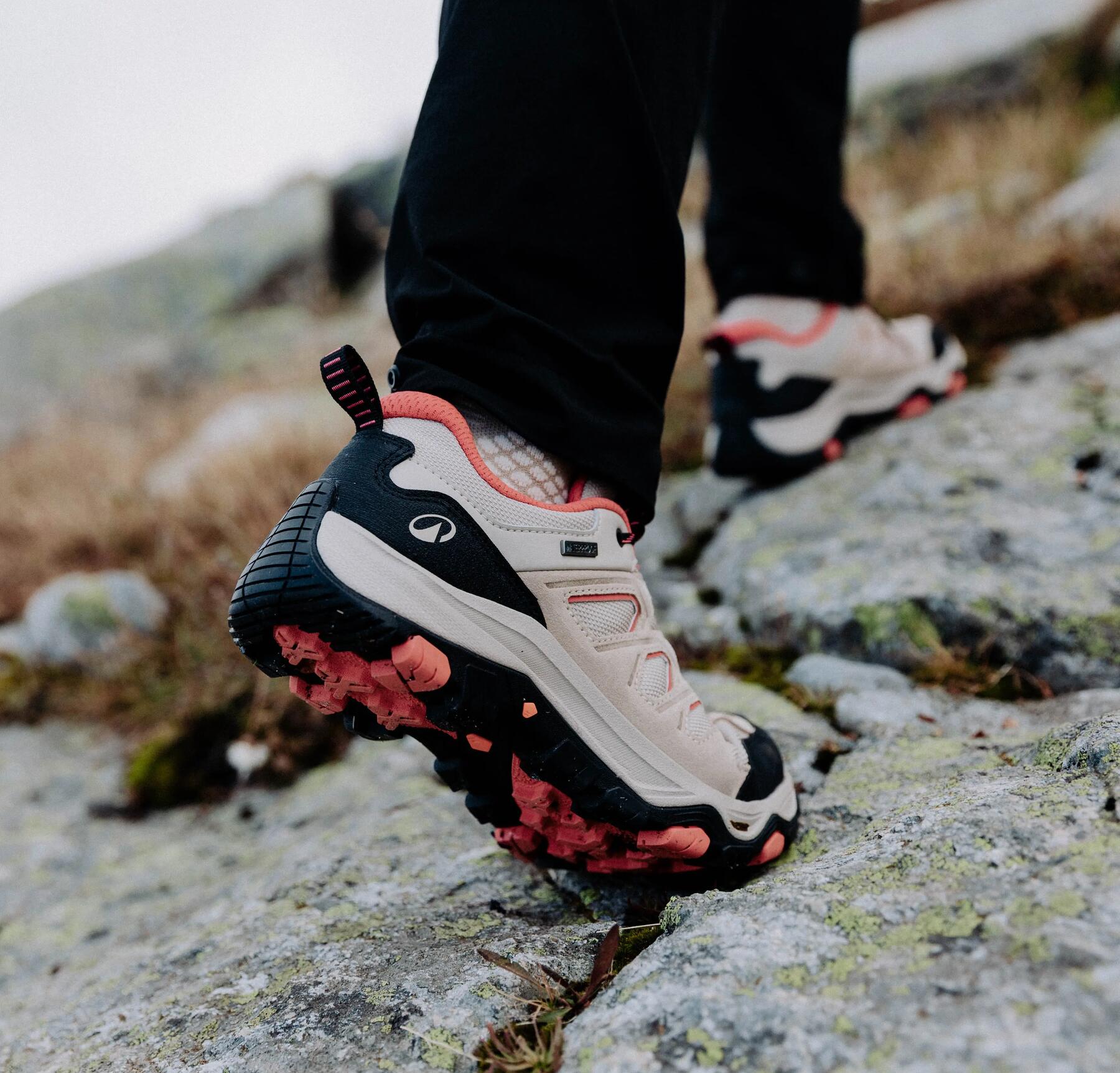 Eine Frau trägt weiß-schwarz-rote Wanderschuhe auf Stein