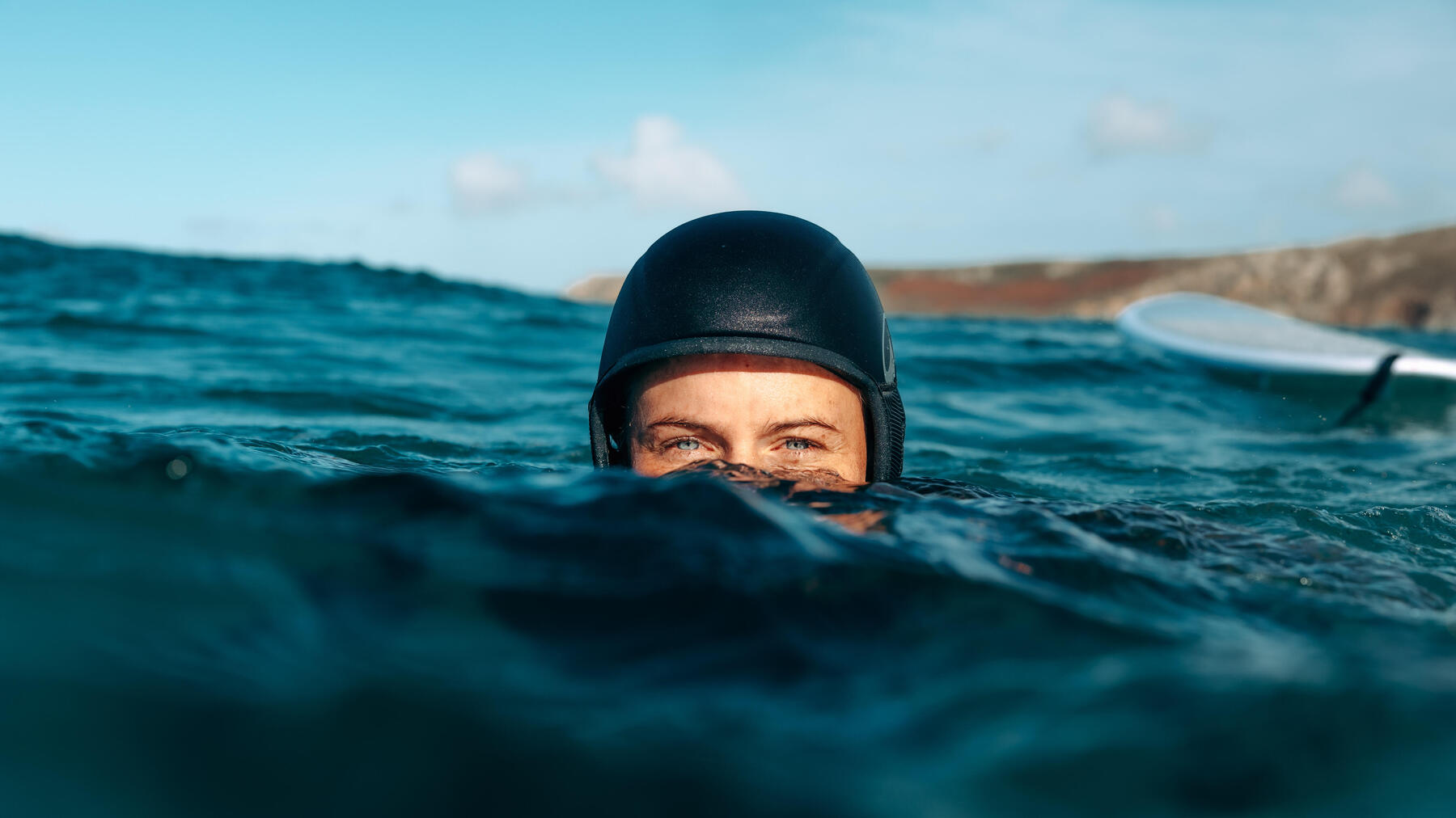 woman walking on a beach to reach the water with her surf board