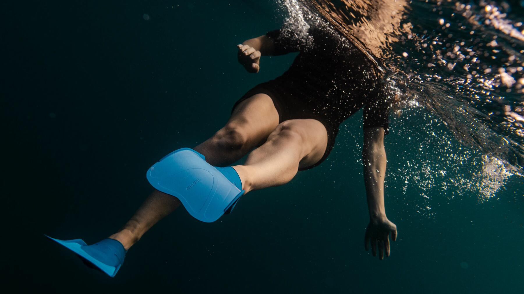 Eine Frau schwimmt mit Tauchflossen im dunklen Wasser