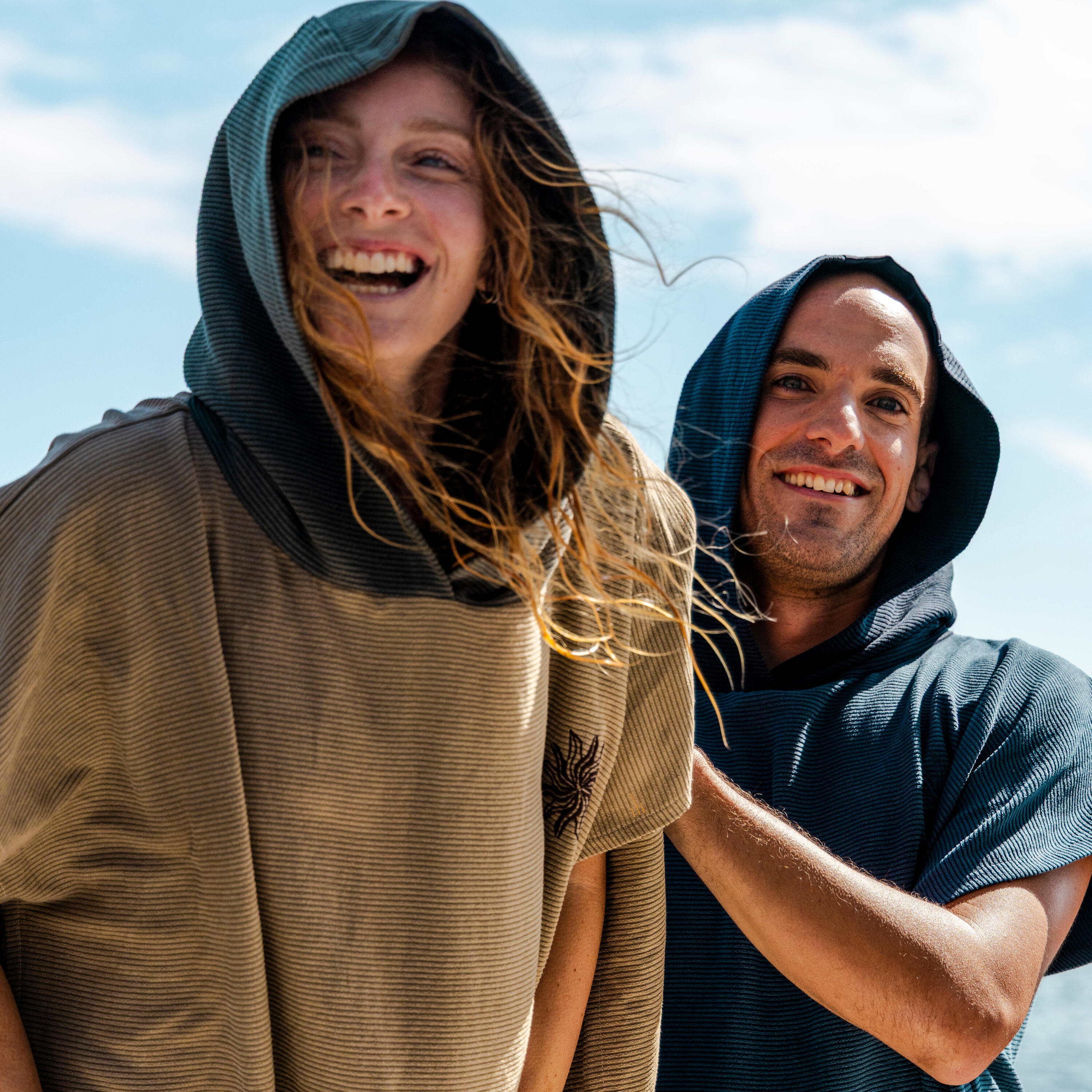 Zwei Personen in Surfponchos grinsen in die Kamera