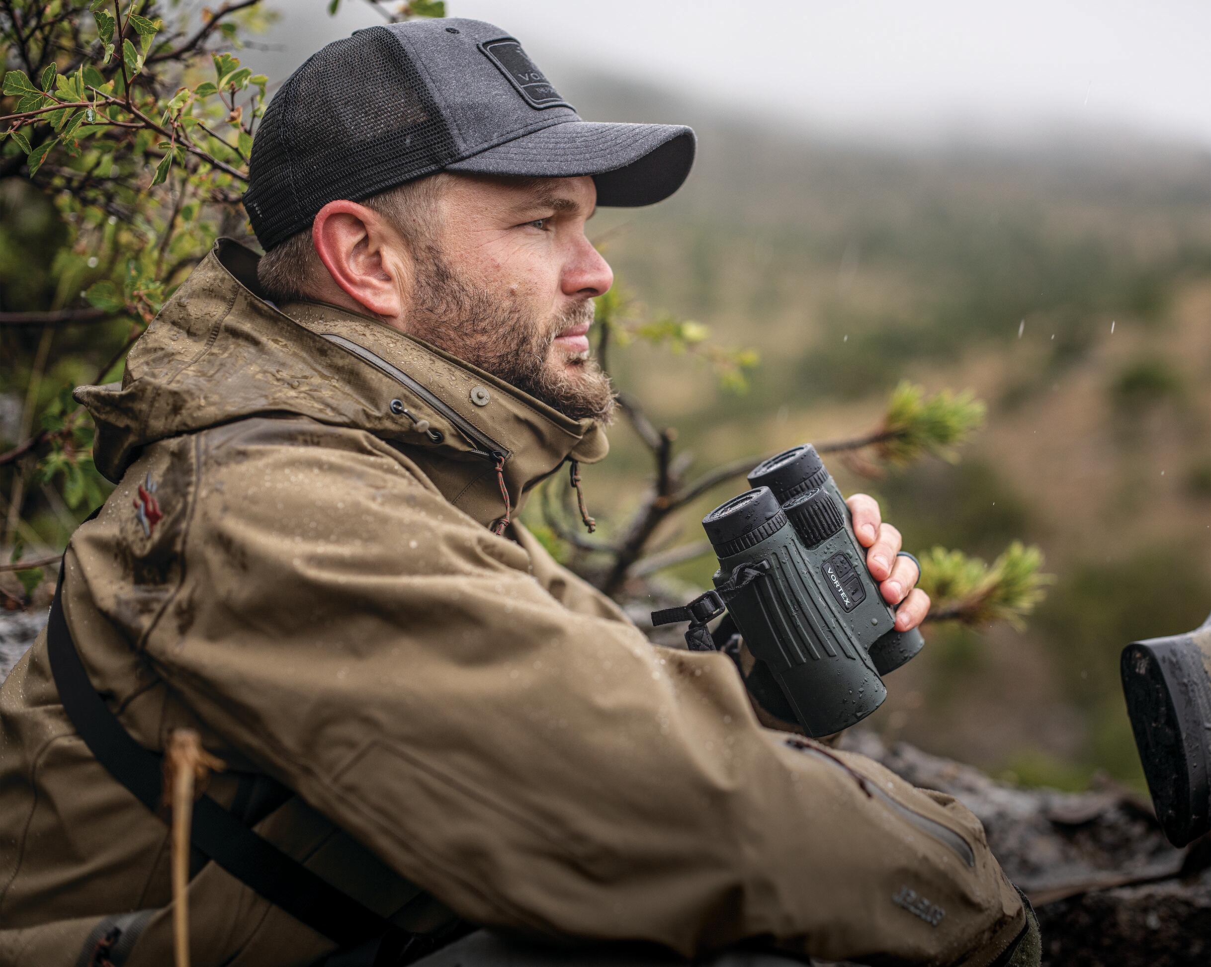 Hunter holding binoculars while observing the landscape
