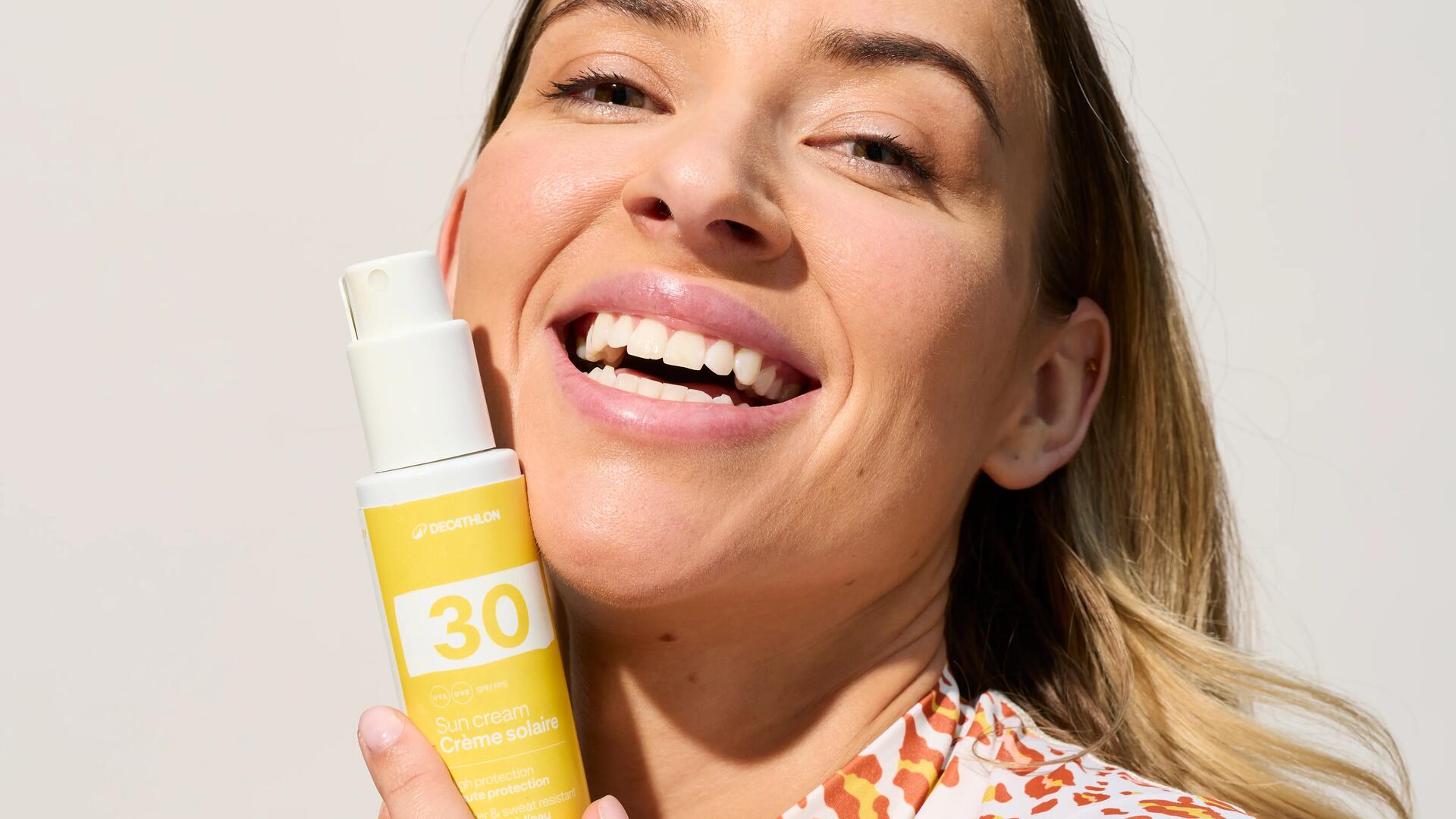 femme tenant un flacon de crème solaire SPF 30