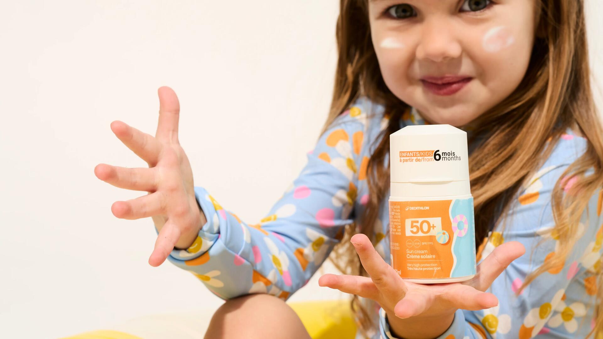 petite fille tenant un flacon de crème solaire