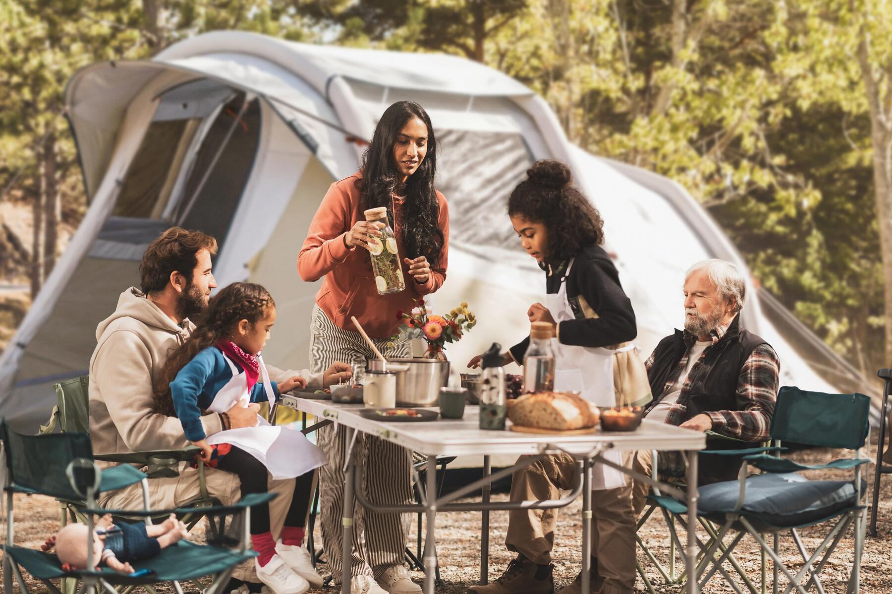 Eine Familie deckt beim Camping den Tisch mit Campinggeschirr