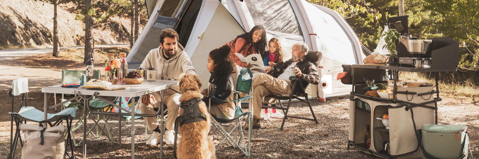 Familie sitzt auf Campingmöbeln vor ihrem Zelt in der Natur!