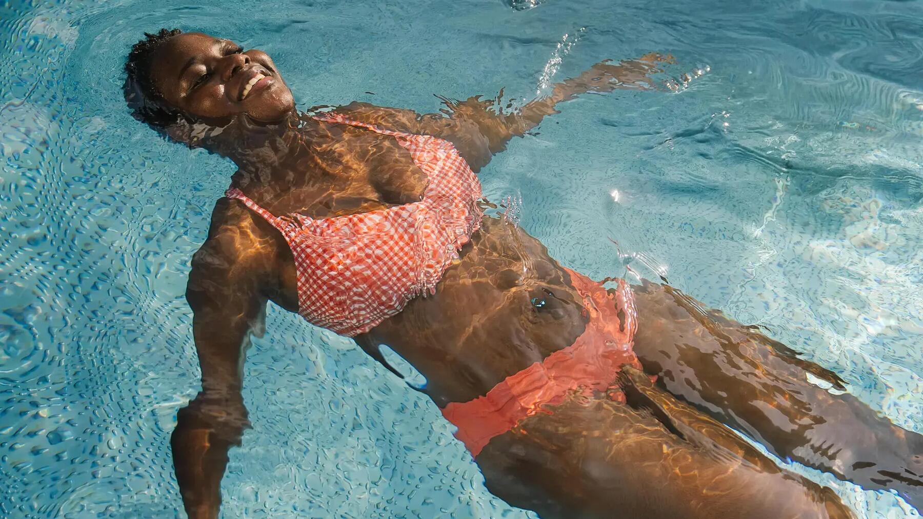 Eine Frau treibt im Wasser gegen Cellulite