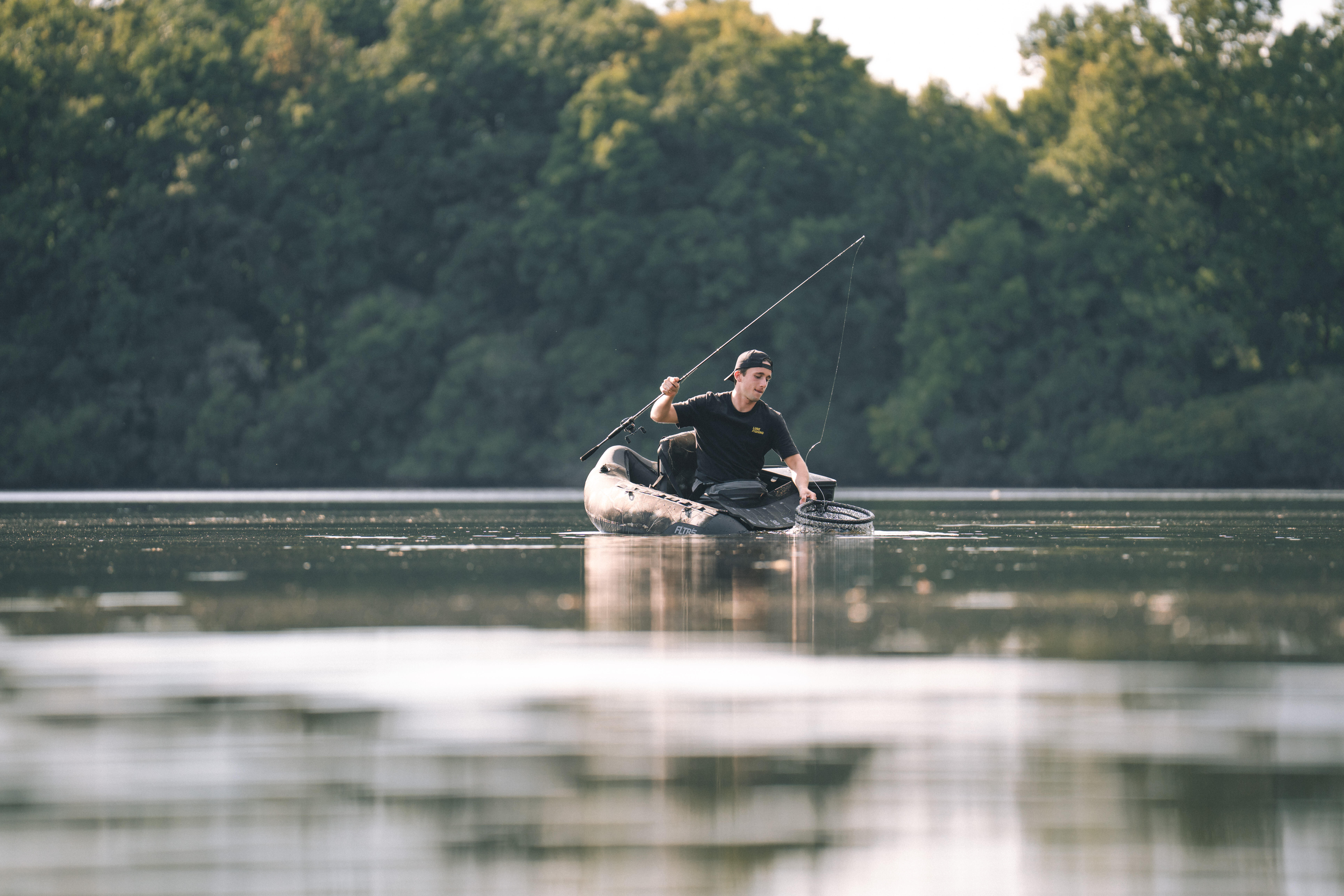 Angler fishing from an inflatable fishing kayak on a calm lake