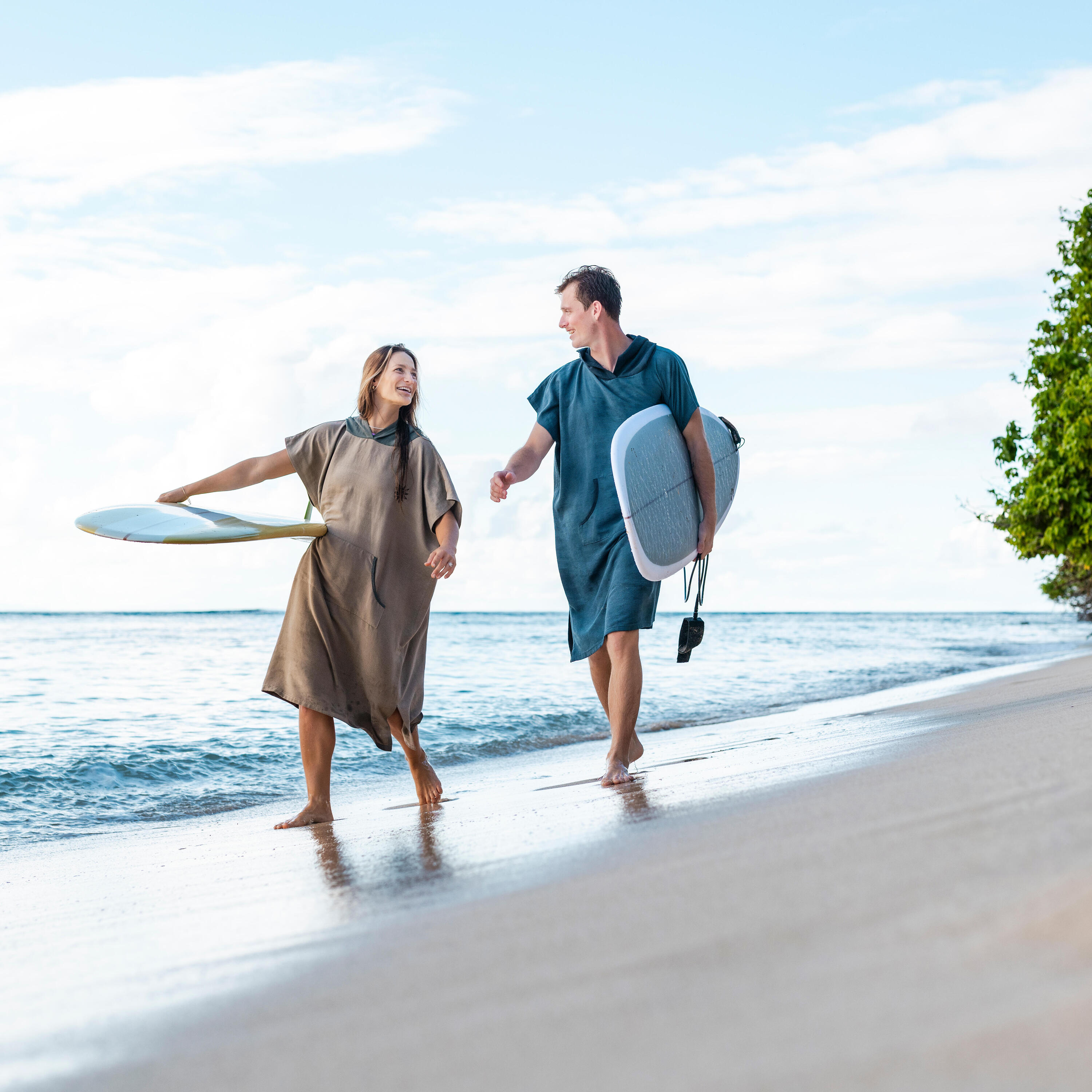 Zwei Personen laufen am Strand mit Surfbrettern in der Hand