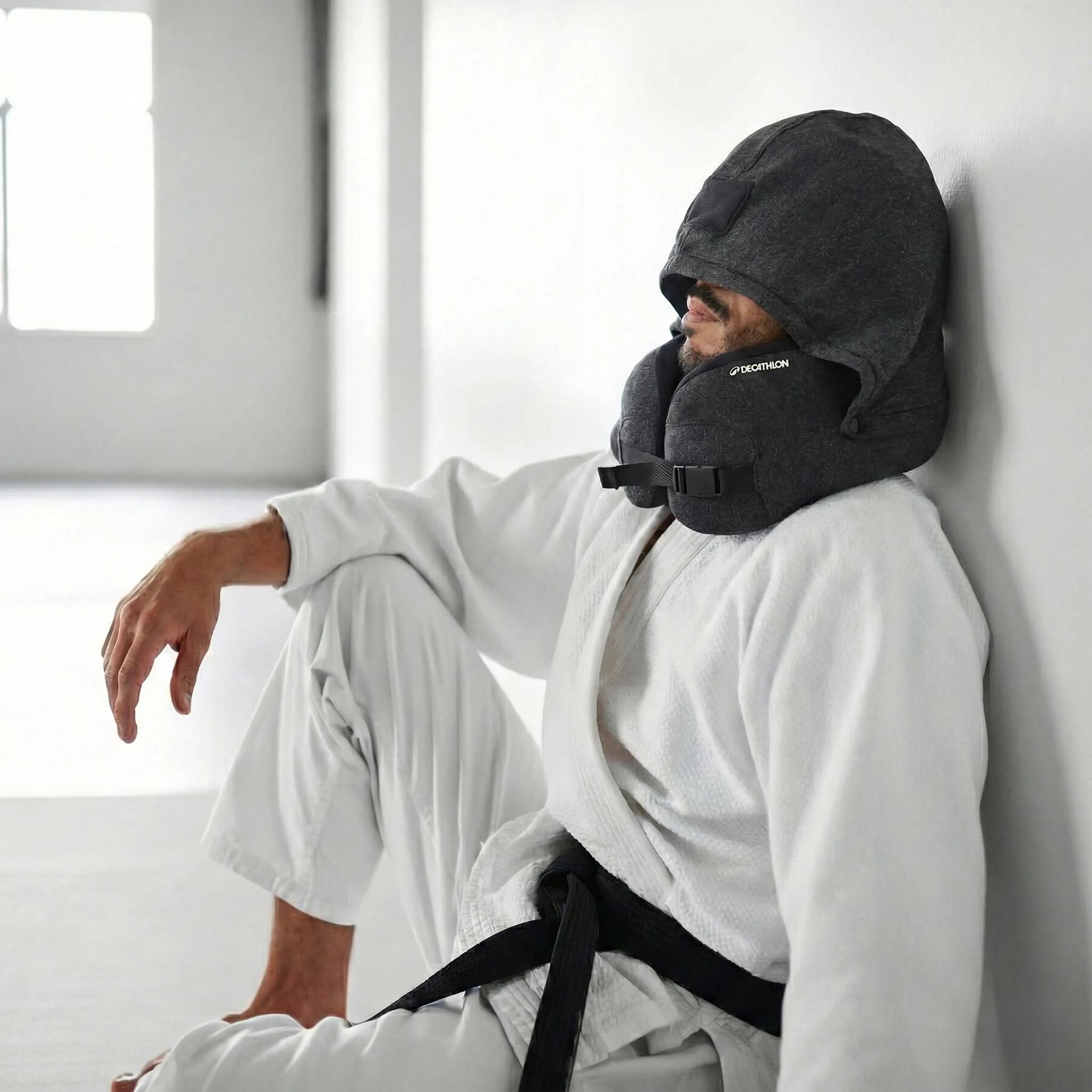 Mann nach dem Karatetraining mit Massagekissen mit integrierter Kapuze auf dem Boden am entspannen