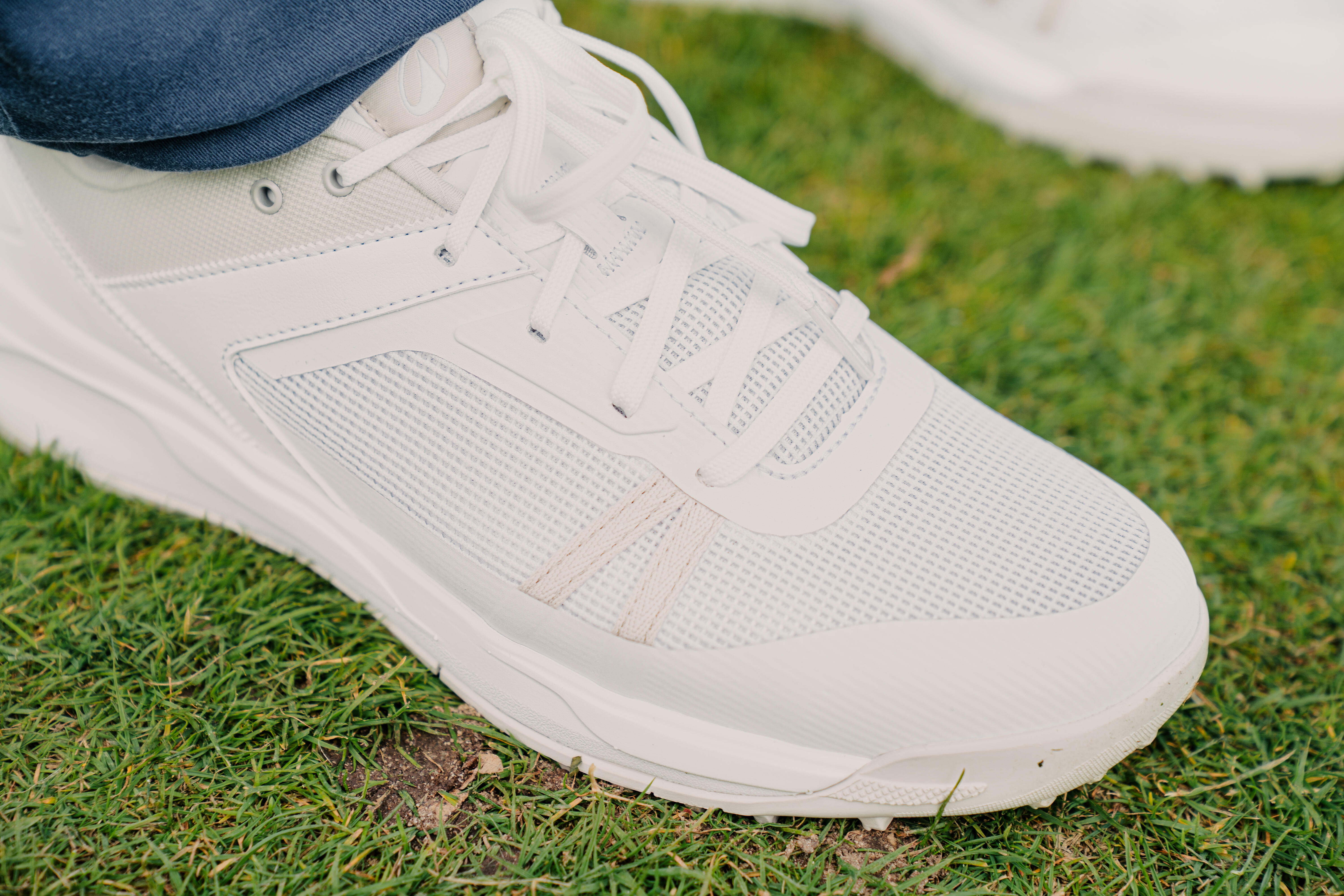 White golf shoe close-up, mesh texture, standing on grass