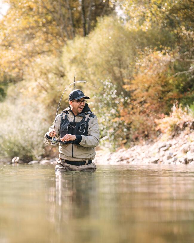 Pêcheur dans la rivière combattant une truite.