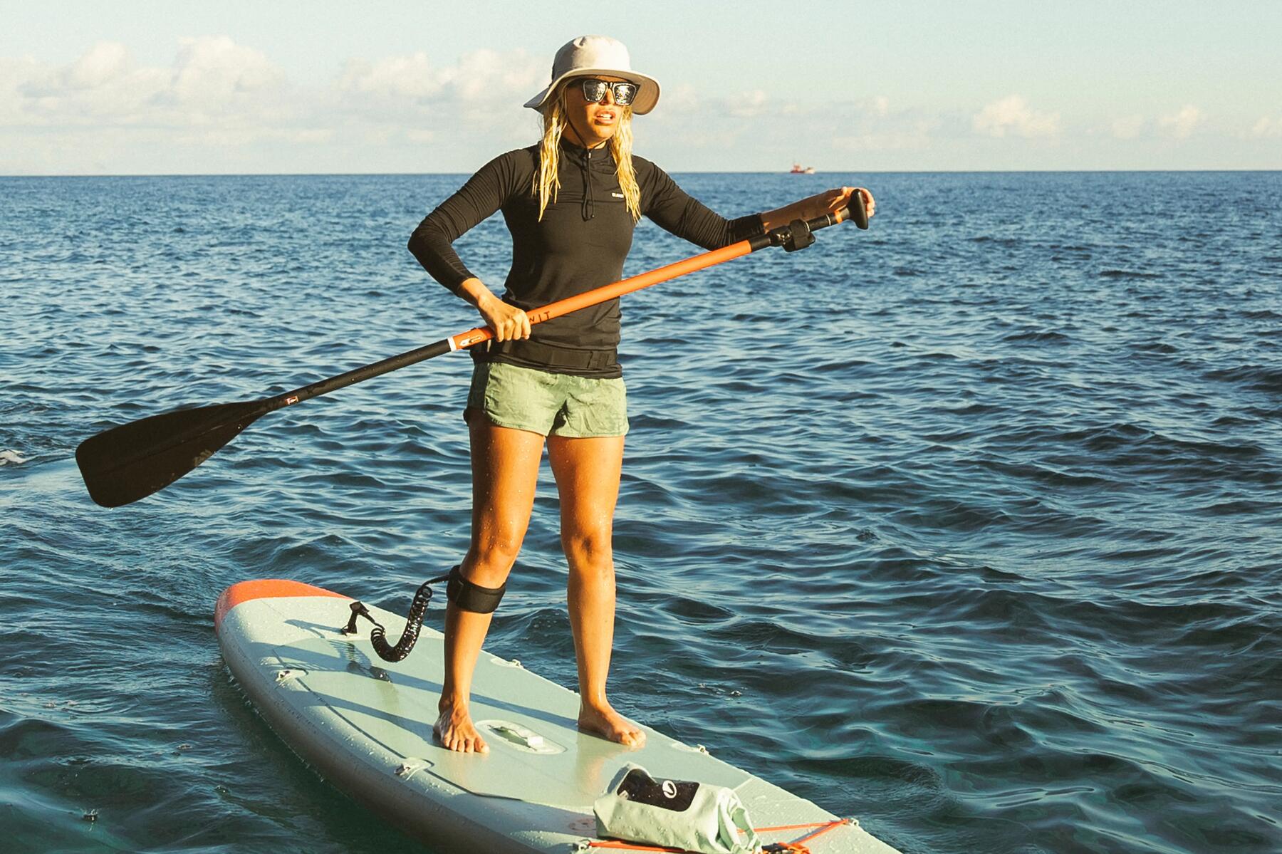 Eine Frau steht auf einem SUP-Board mit Paddel