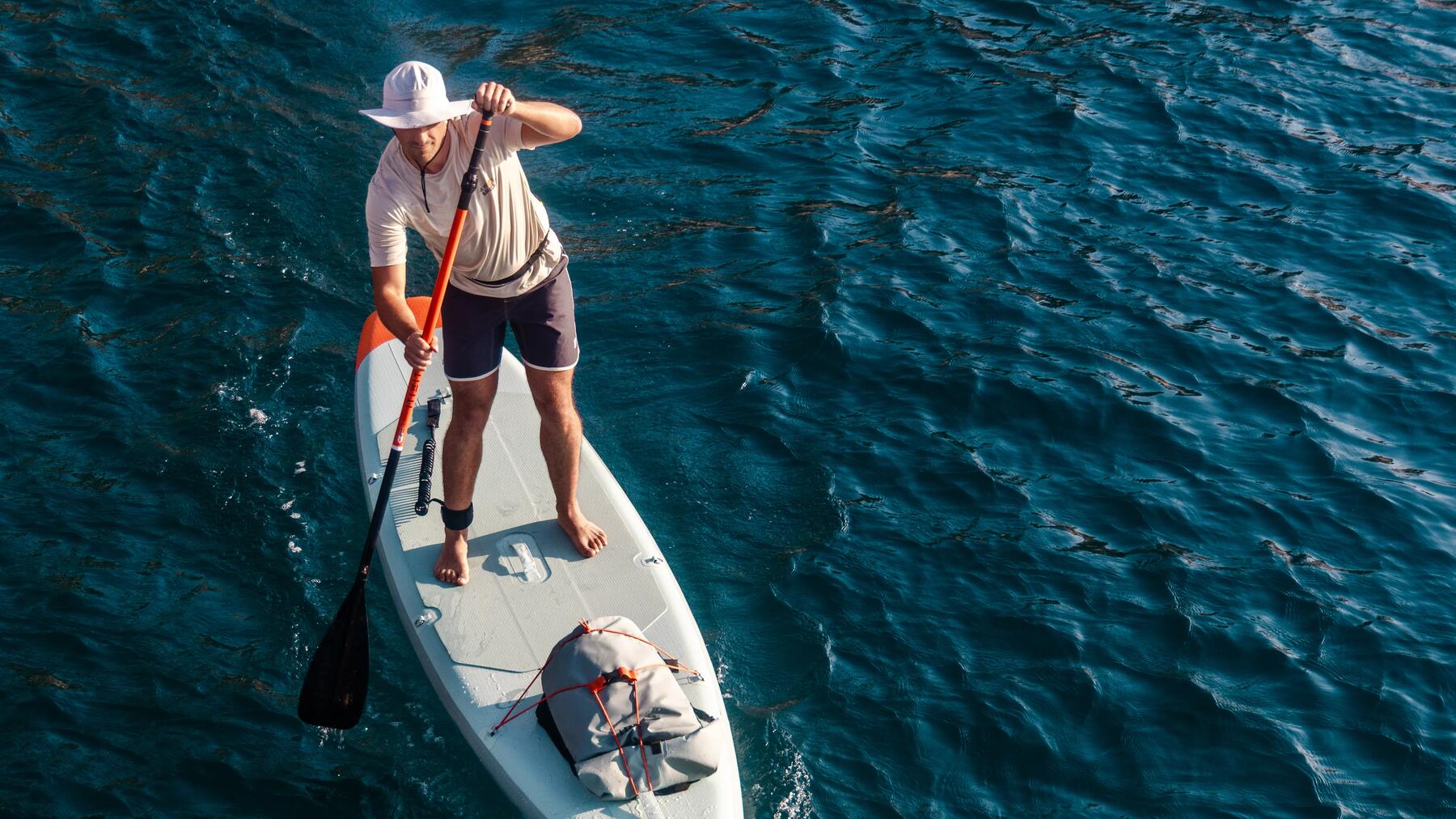 Ein Mann steht auf einem SUP auf dem Meer