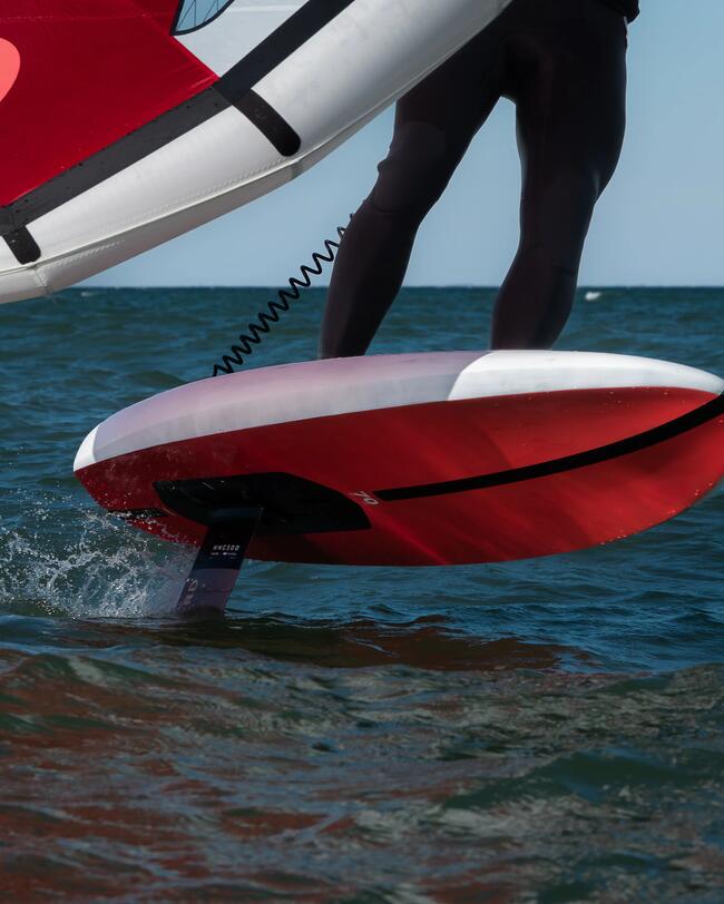 pratiquant de wing foil sur une planche rouge, avec une wing rouge decathlon